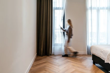 Une femme regarde dehors ĂÂ  travers les rideaux d'une chambre d'hĂÂ´tel